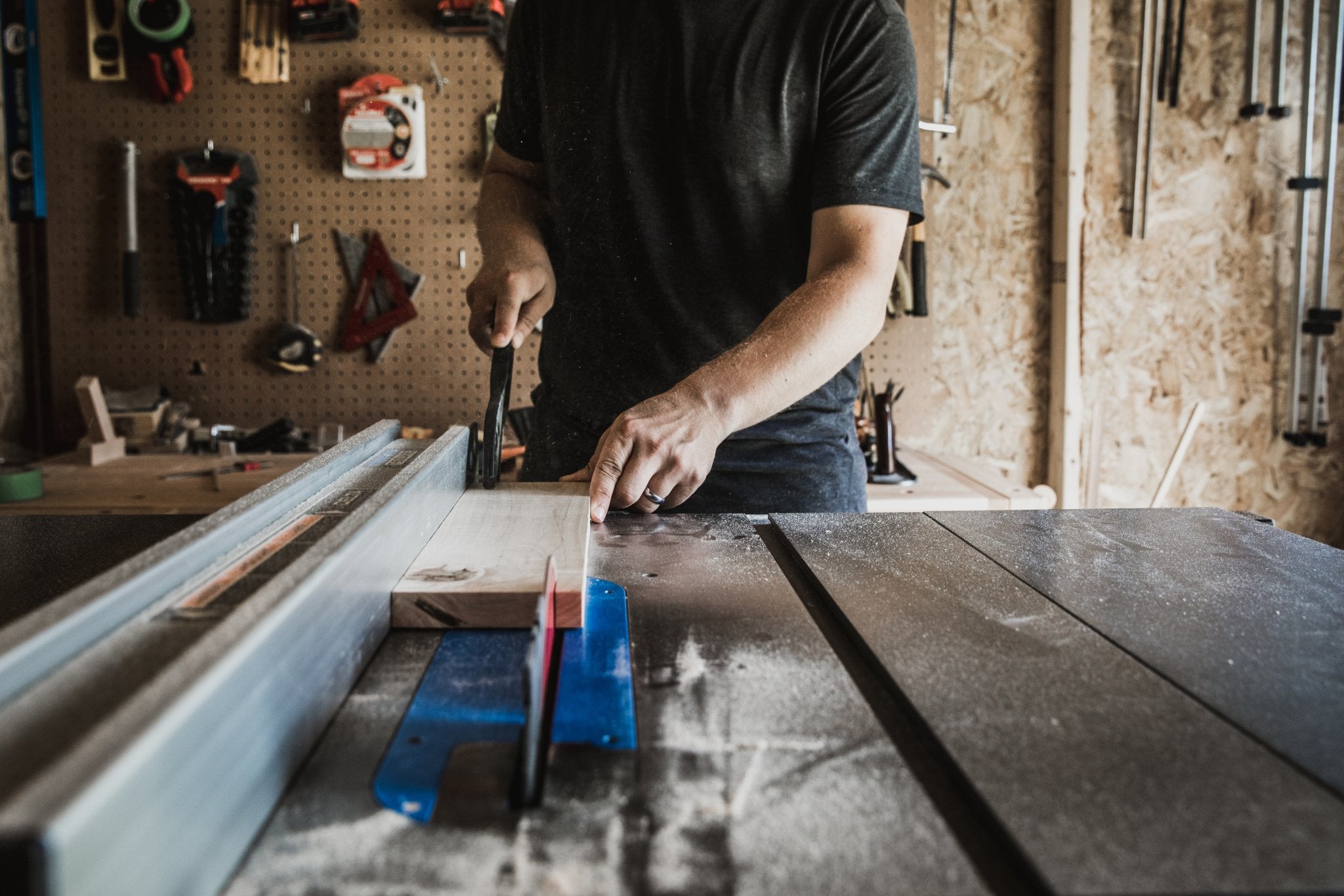 a man pushing wood through a table saw